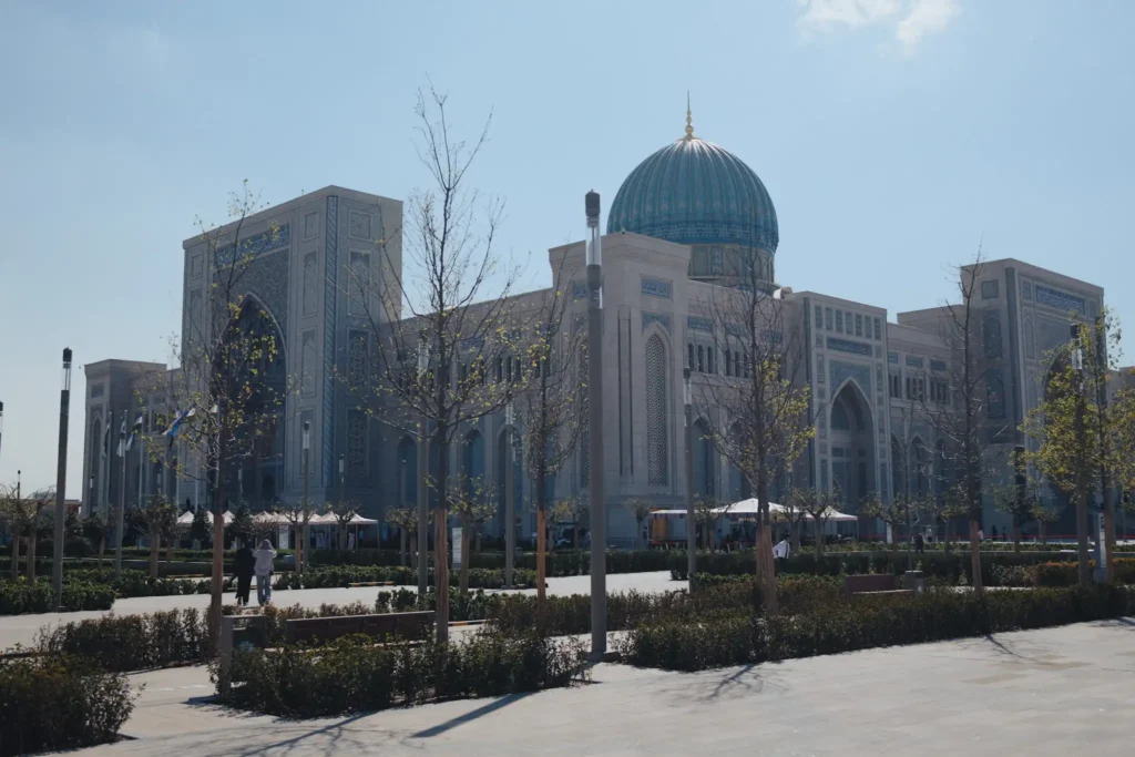 Güneşli bir günde Taşkent'teki Özbekistan İslam Medeniyeti Merkezi'nin turkuaz kubbeli dış cephesi ve önündeki park alanı.
